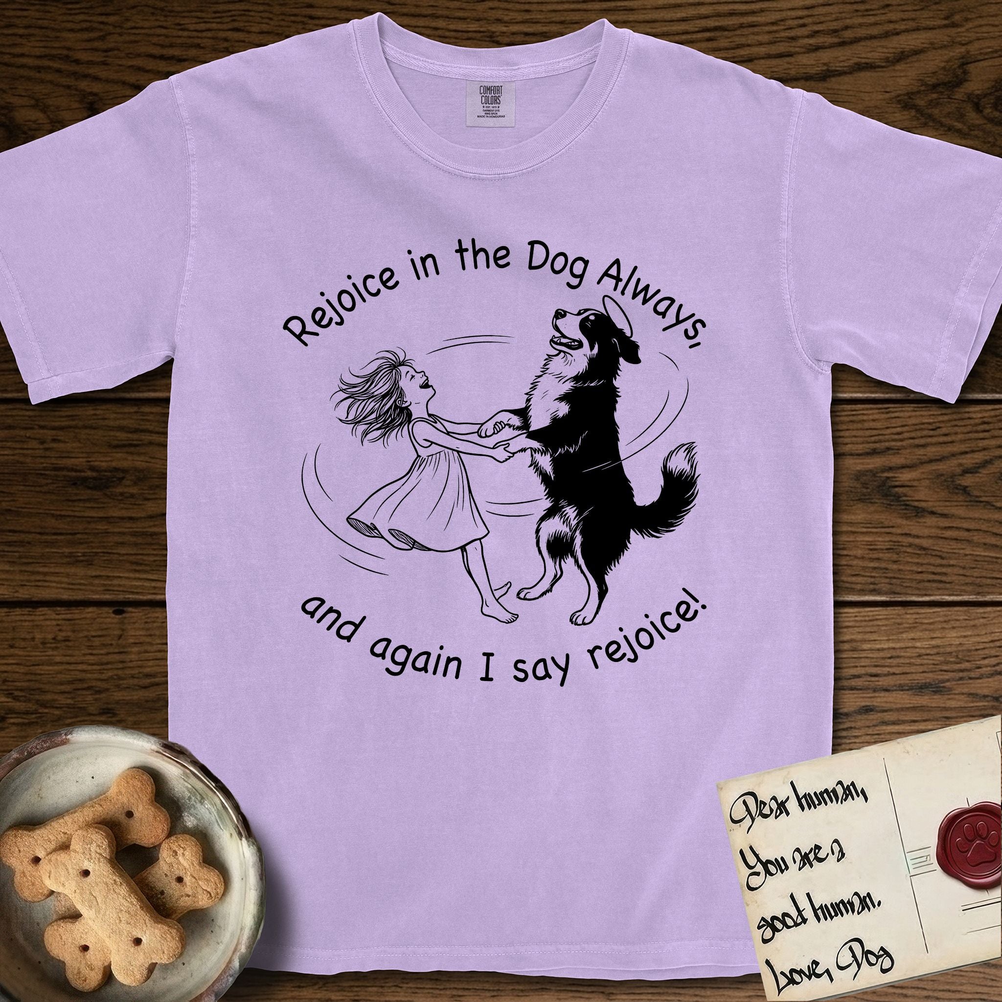 Rejoice in the Dog Bernese Mountain Dog T-Shirt flat lay in Orchid, featuring a sparse pen-and-ink illustration of a girl and her Bernese Mountain Dog spinning together, her feet lifting off the ground.