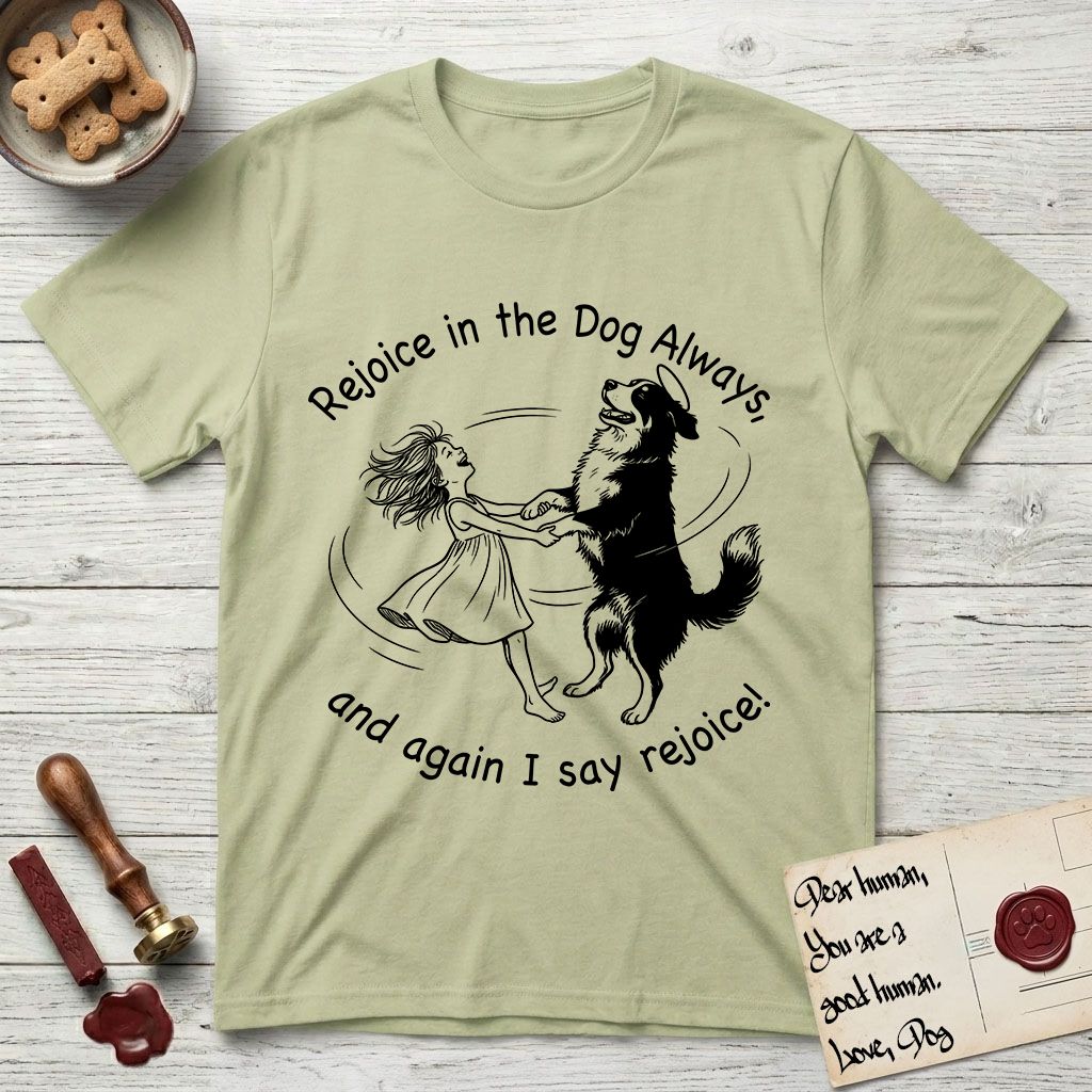 Rejoice in the Dog Bernese Mountain Dog T-Shirt flat lay in Pistachio, featuring a sparse pen-and-ink illustration of a girl and her Bernese Mountain Dog spinning together, her feet lifting off the ground.