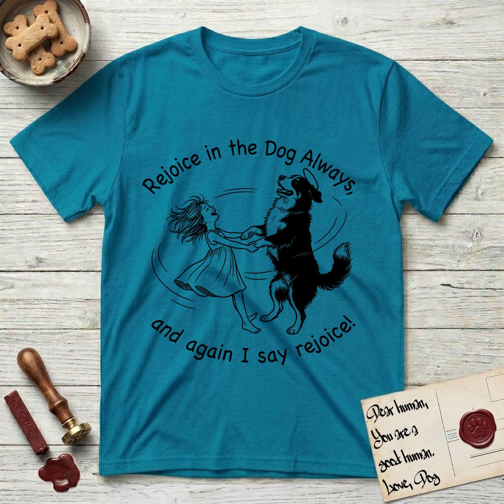 Rejoice in the Dog Bernese Mountain Dog T-Shirt flat lay in Tropical Blue, featuring a sparse pen-and-ink illustration of a girl and her Bernese Mountain Dog spinning together, her feet lifting off the ground.