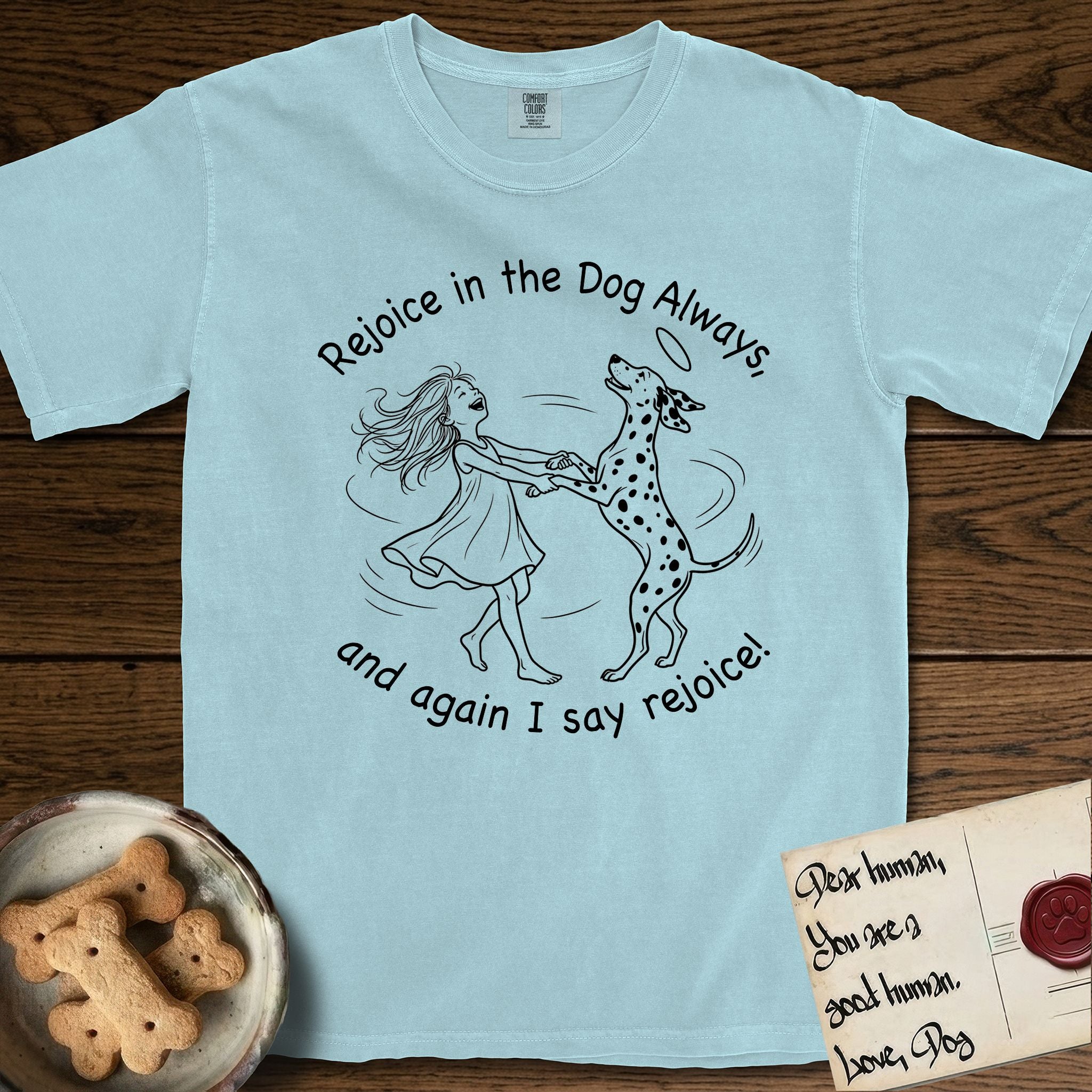 Rejoice in the Dog Dalmatian T-Shirt flat lay in Chambray, featuring a sparse pen-and-ink illustration of a girl and her Dalmatian spinning together, both heads thrown back in joy.