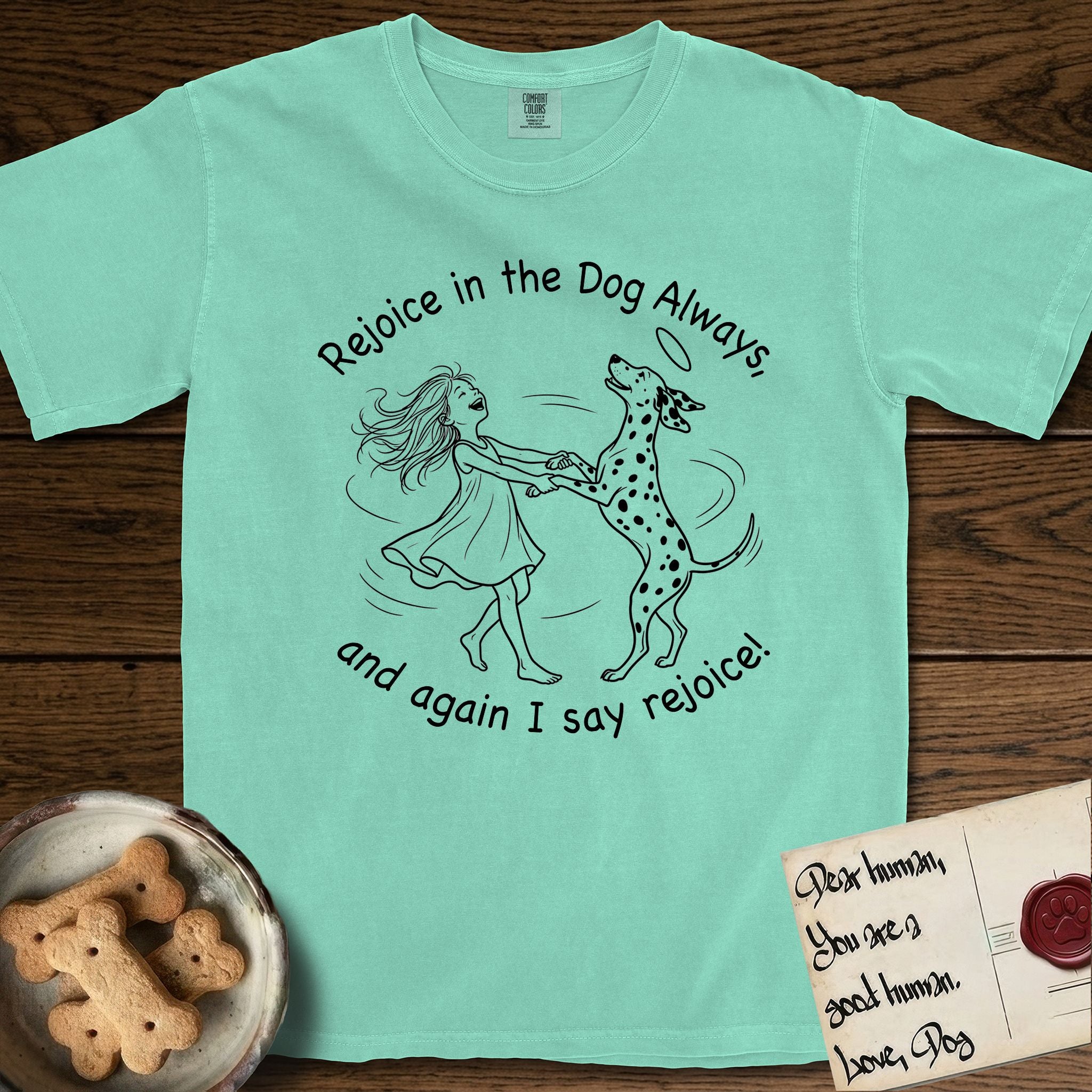 Rejoice in the Dog Dalmatian T-Shirt flat lay in Island Reef, featuring a sparse pen-and-ink illustration of a girl and her Dalmatian spinning together, both heads thrown back in joy.