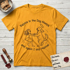 Rejoice in the Dog Goldendoodle T-Shirt flat lay in Gold, featuring a sparse pen-and-ink illustration of a girl and her Goldendoodle dancing together, fur flying, both heads thrown back.