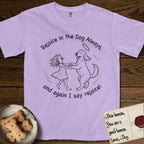 Rejoice in the Dog Goldendoodle T-Shirt flat lay in Orchid, featuring a sparse pen-and-ink illustration of a girl and her Goldendoodle dancing together, fur flying, both heads thrown back.