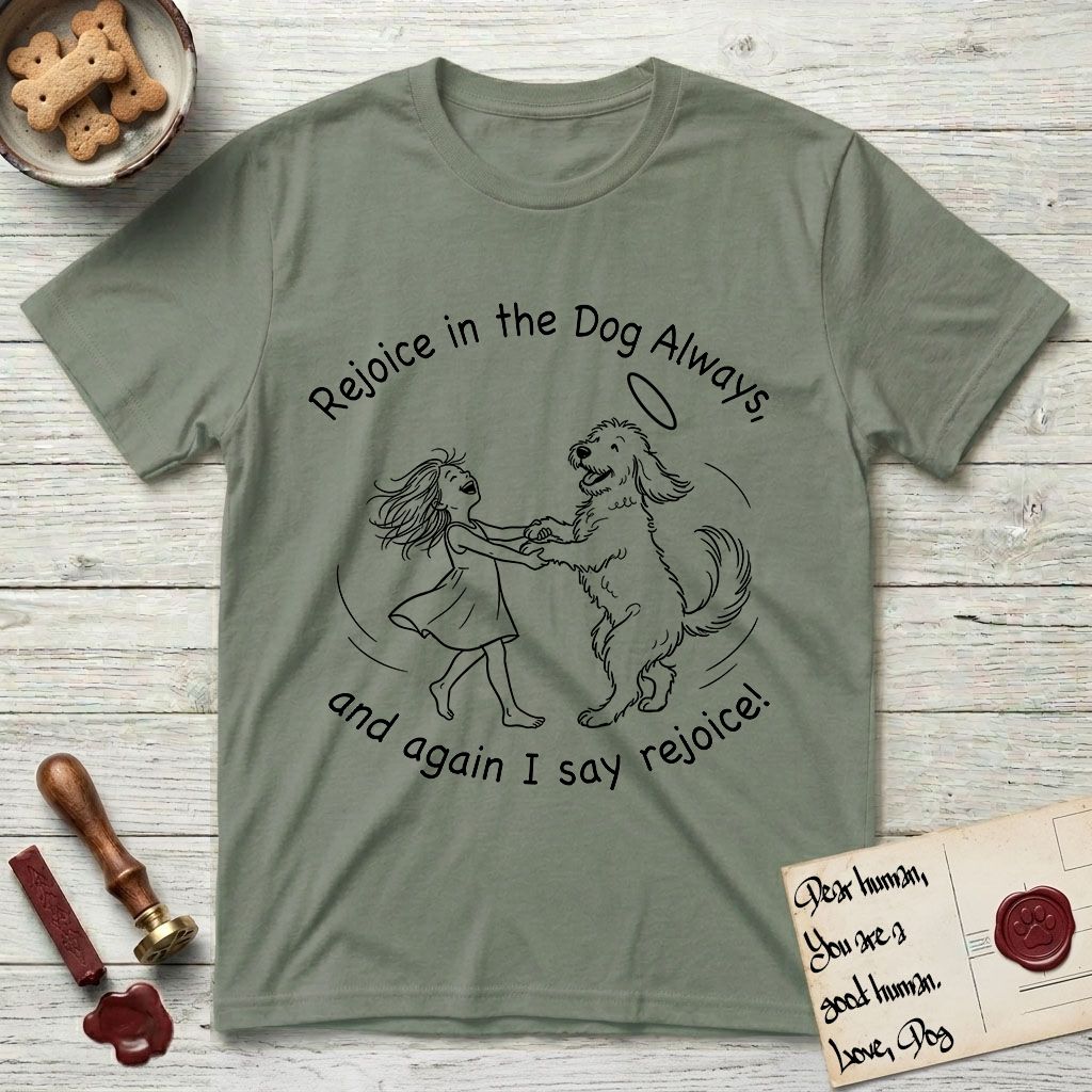Rejoice in the Dog Goldendoodle T-Shirt flat lay in Sage, featuring a sparse pen-and-ink illustration of a girl and her Goldendoodle dancing together, fur flying, both heads thrown back.