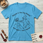 Rejoice in the Dog Goldendoodle T-Shirt flat lay in Sky, featuring a sparse pen-and-ink illustration of a girl and her Goldendoodle dancing together, fur flying, both heads thrown back.