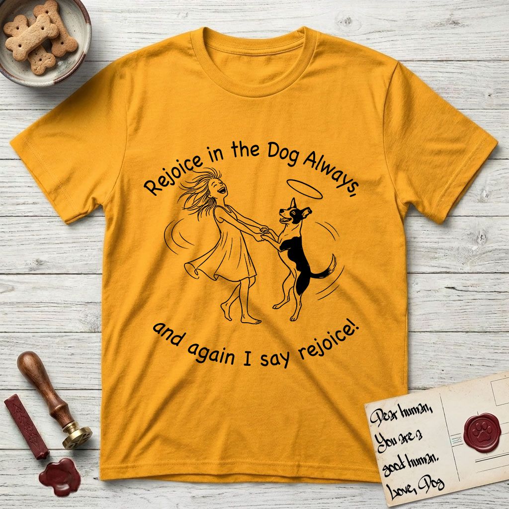 Rejoice in the Dog Lobo T-Shirt flat lay in Gold, featuring a sparse pen-and-ink illustration of a girl and her haloed Dog Lobo spinning together, hands and paws clasped.
