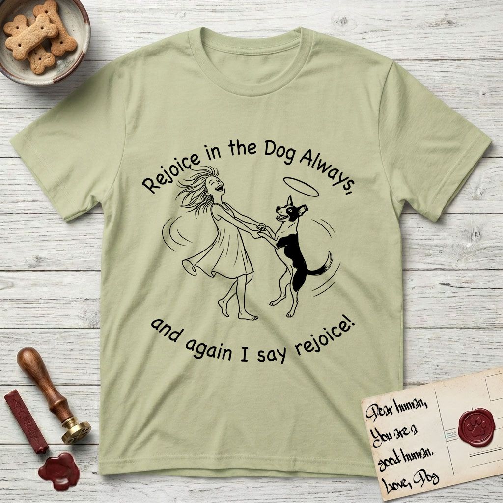 Rejoice in the Dog Lobo T-Shirt flat lay in Pistachio, featuring a sparse pen-and-ink illustration of a girl and her haloed Dog Lobo spinning together, hands and paws clasped.