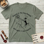 Rejoice in the Dog Lobo T-Shirt flat lay in Sage, featuring a sparse pen-and-ink illustration of a girl and her haloed Dog Lobo spinning together, hands and paws clasped.