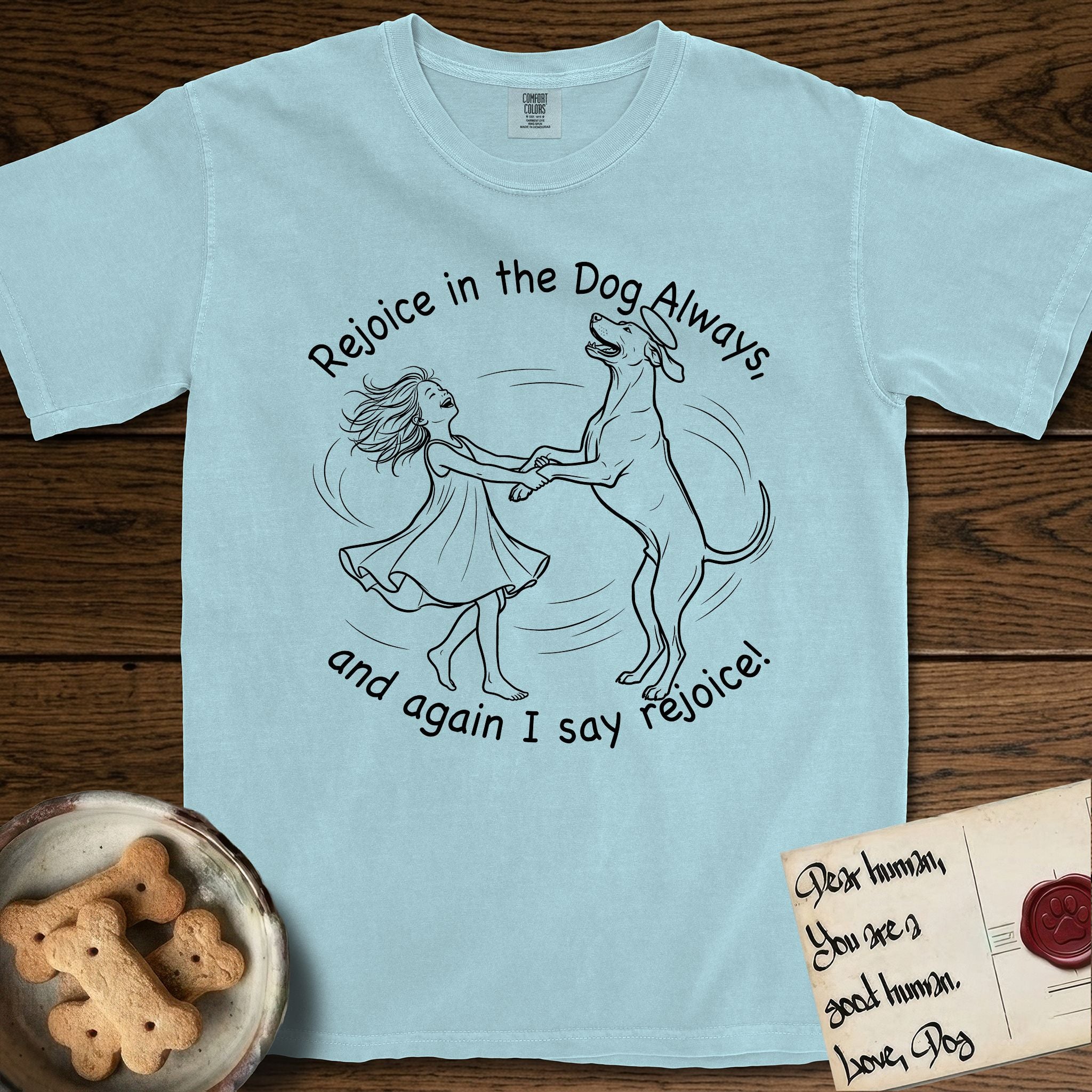 Rejoice in the Dog Rhodesian Ridgeback T-Shirt flat lay in Chambray, featuring a sparse pen-and-ink illustration of a girl and her Rhodesian Ridgeback spinning together, hands and paws clasped.