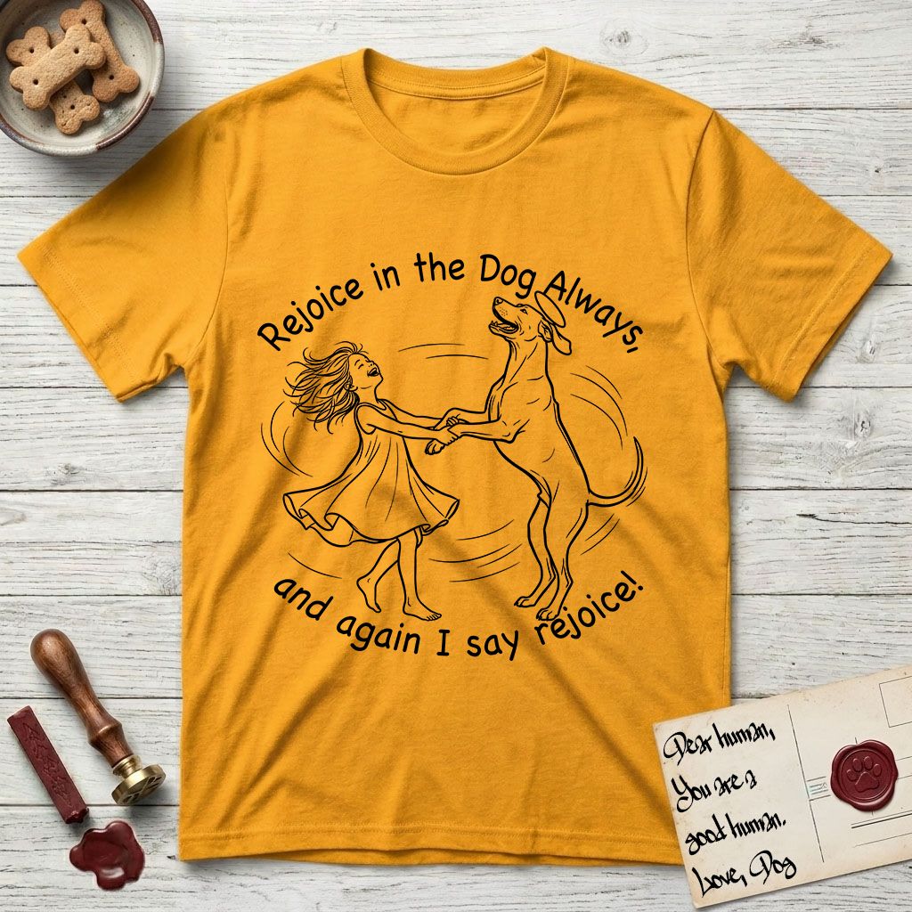 Rejoice in the Dog Rhodesian Ridgeback T-Shirt flat lay in Gold, featuring a sparse pen-and-ink illustration of a girl and her Rhodesian Ridgeback spinning together, hands and paws clasped.