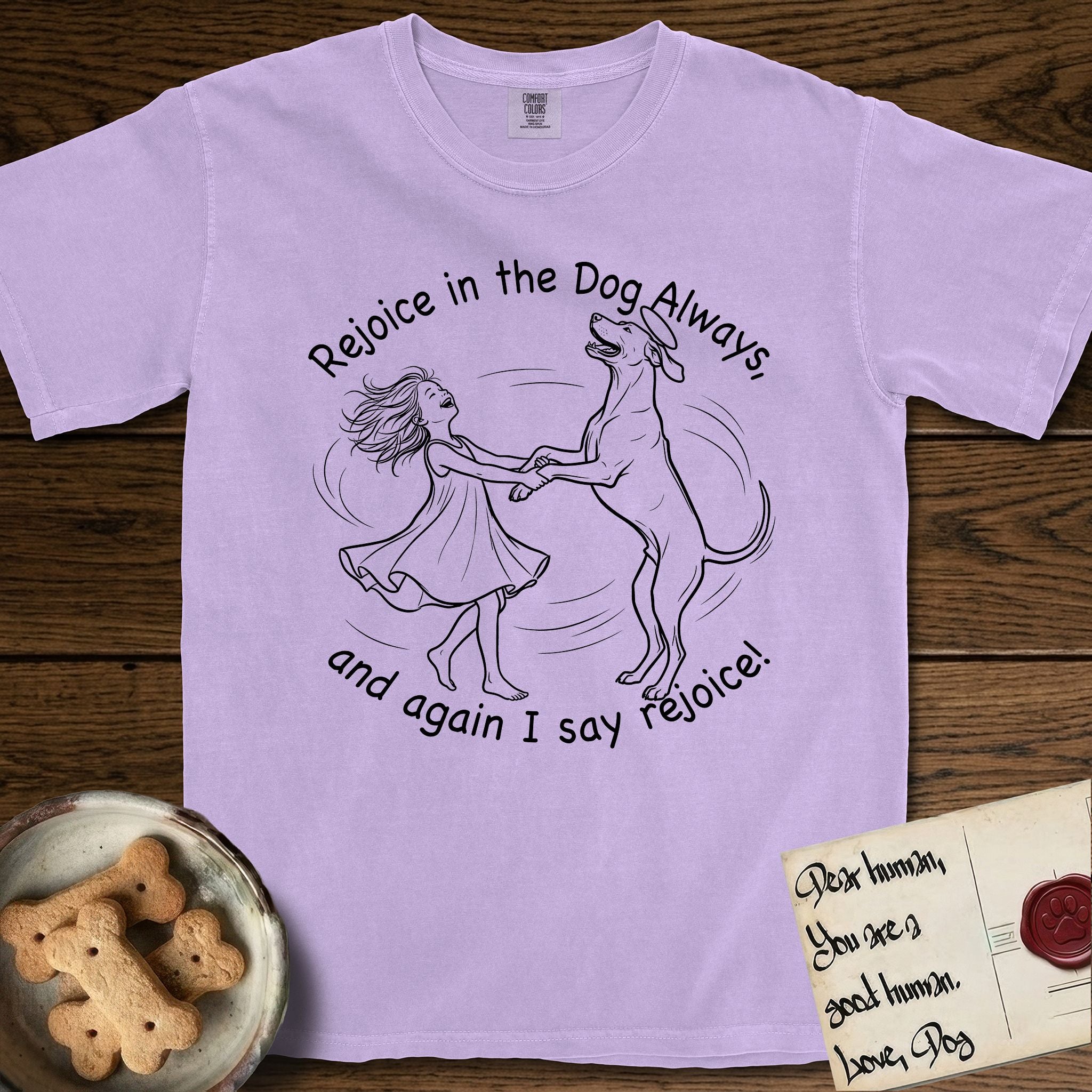 Rejoice in the Dog Rhodesian Ridgeback T-Shirt flat lay in Orchid, featuring a sparse pen-and-ink illustration of a girl and her Rhodesian Ridgeback spinning together, hands and paws clasped.