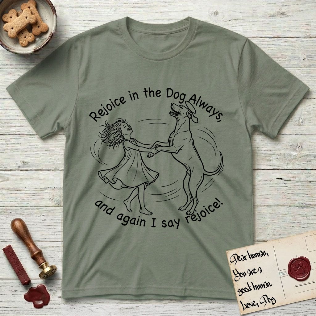 Rejoice in the Dog Rhodesian Ridgeback T-Shirt flat lay in Sage, featuring a sparse pen-and-ink illustration of a girl and her Rhodesian Ridgeback spinning together, hands and paws clasped.