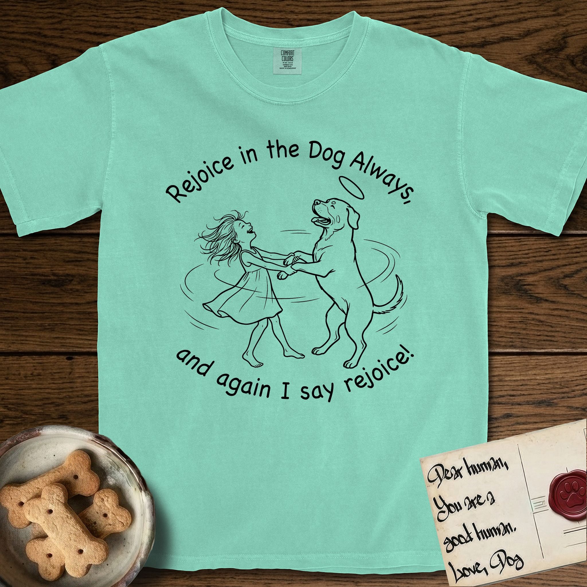 Rejoice in the Dog Rottweiler T-Shirt flat lay in Island Reef, featuring a sparse pen-and-ink illustration of a girl and her Rottweiler dancing on her hind legs, both heads thrown back in joy.