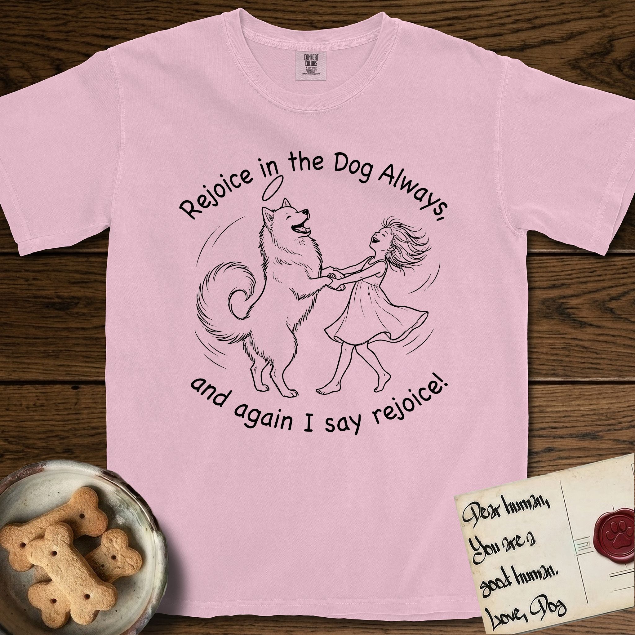 Rejoice in the Dog Samoyed T-Shirt flat lay in Blossom, featuring a sparse pen-and-ink illustration of a girl and her smiling Samoyed spinning together, hands and paws clasped.