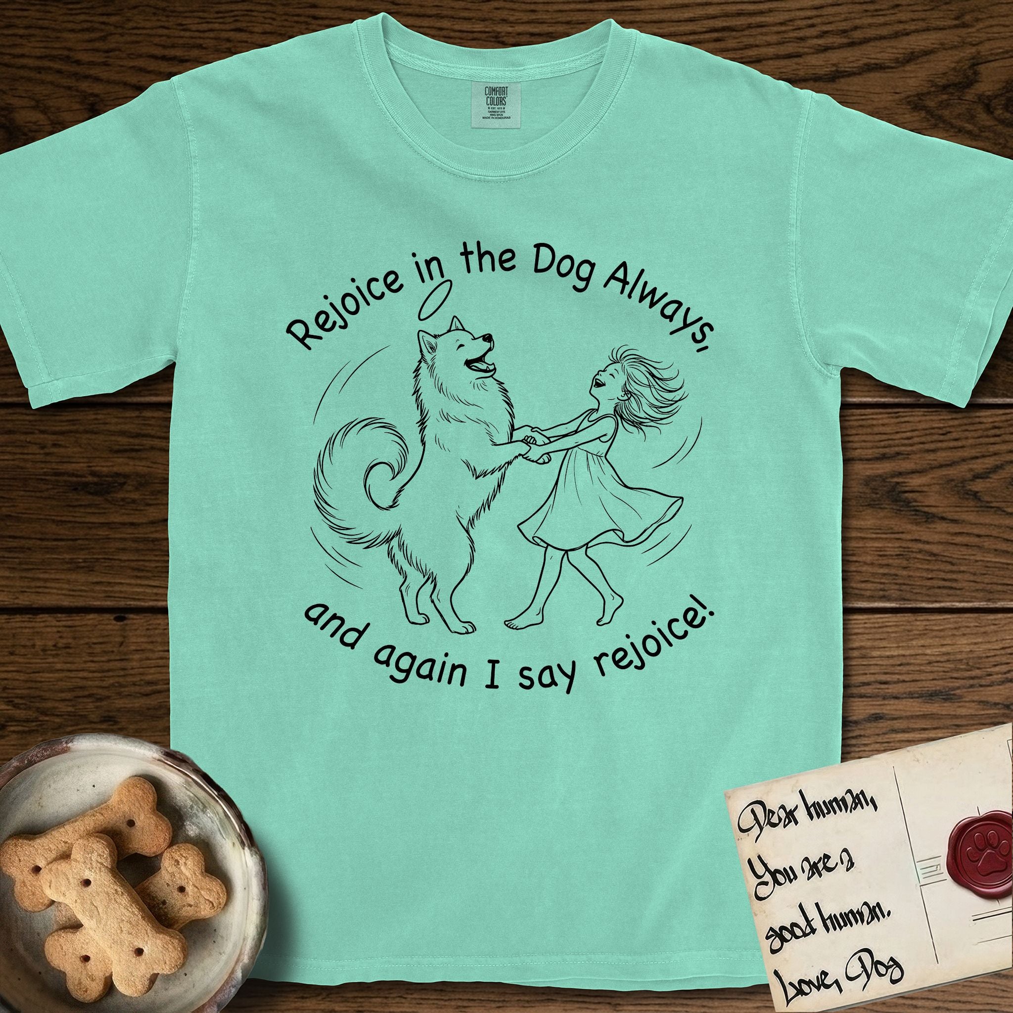 Rejoice in the Dog Samoyed T-Shirt flat lay in Island Reef, featuring a sparse pen-and-ink illustration of a girl and her smiling Samoyed spinning together, hands and paws clasped.