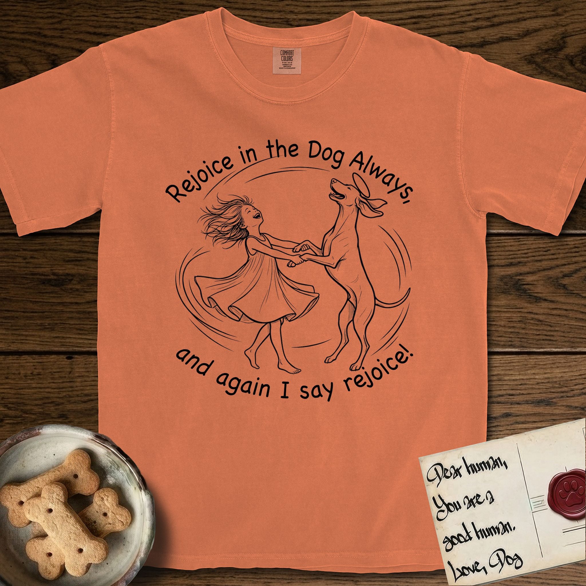 Rejoice in the Dog Vizsla T-Shirt flat lay in Melon, featuring a sparse pen-and-ink illustration of a girl and her Vizsla spinning together, hands and paws clasped.