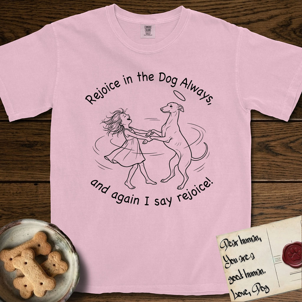 Rejoice in the Dog Whippet T-Shirt flat lay in Blossom, featuring a sparse pen-and-ink illustration of a girl and her Whippet dancing on his hind legs, both heads thrown back in joy.