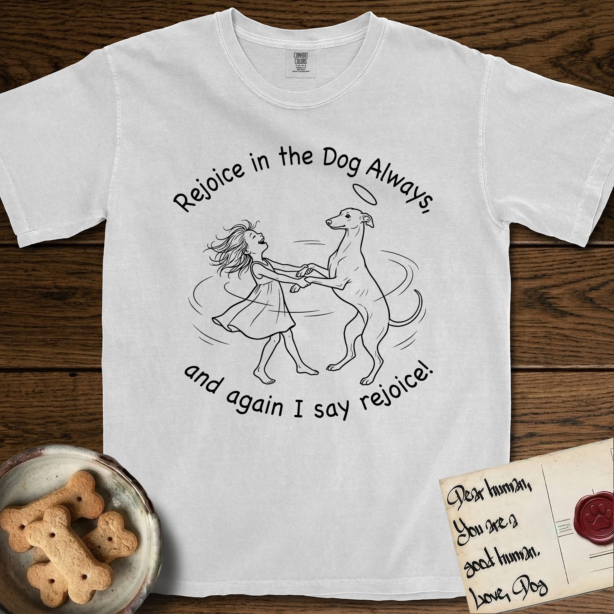Rejoice in the Dog Whippet T-Shirt flat lay in White, featuring a sparse pen-and-ink illustration of a girl and her Whippet dancing on his hind legs, both heads thrown back in joy.