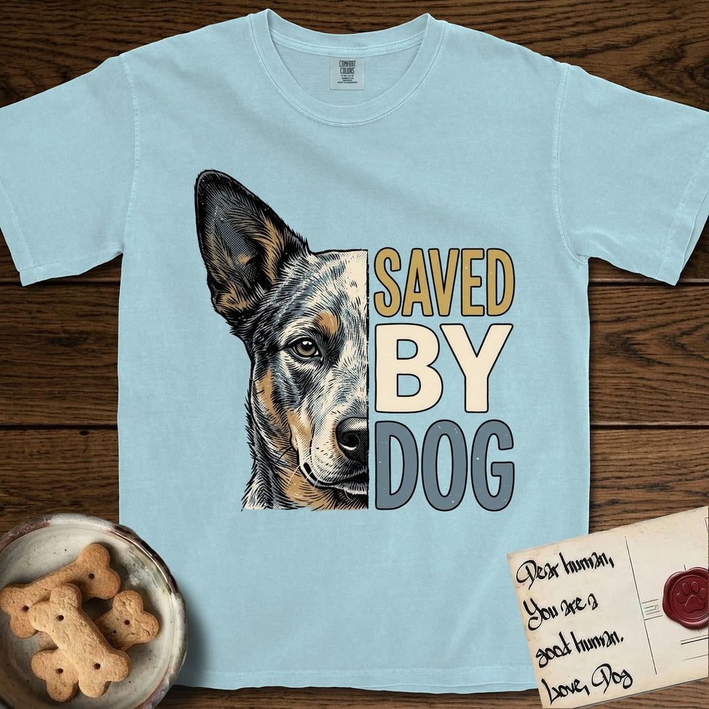 Saved by Dog Australian Cattle Dog T-Shirt flat lay in Chambray, featuring half an Australian Cattle Dog's face in distressed vintage screen print, blue-speckled with tan points and one amber eye, cropped down the centerline beside bold stacked block lettering.