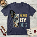 Saved by Dog Australian Cattle Dog T-Shirt flat lay in Navy, featuring half an Australian Cattle Dog's face in distressed vintage screen print, blue-speckled with tan points and one amber eye, cropped down the centerline beside bold stacked block lettering.