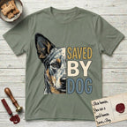 Saved by Dog Australian Cattle Dog T-Shirt flat lay in Sage, featuring half an Australian Cattle Dog's face in distressed vintage screen print, blue-speckled with tan points and one amber eye, cropped down the centerline beside bold stacked block lettering.