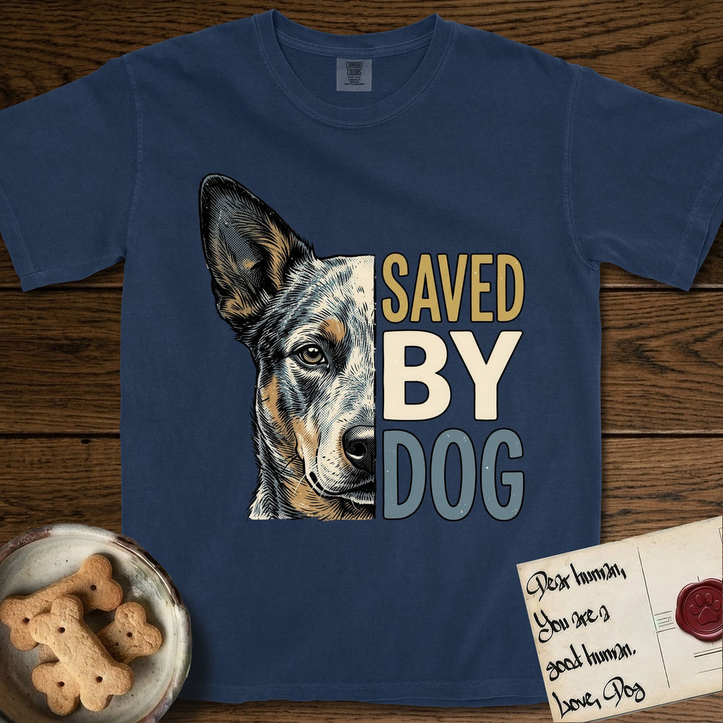 Saved by Dog Australian Cattle Dog T-Shirt flat lay in True Navy, featuring half an Australian Cattle Dog's face in distressed vintage screen print, blue-speckled with tan points and one amber eye, cropped down the centerline beside bold stacked block lettering.