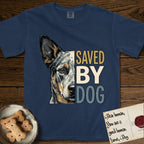 Saved by Dog Australian Cattle Dog T-Shirt flat lay in True Navy, featuring half an Australian Cattle Dog's face in distressed vintage screen print, blue-speckled with tan points and one amber eye, cropped down the centerline beside bold stacked block lettering.