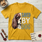 Saved by Dog Cavalier T-Shirt flat lay in Daisy, featuring half a chestnut-and-white Cavalier's face in distressed vintage screen print, one long feathered ear and a large soft eye, cropped down the centerline beside bold stacked block lettering.