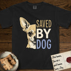 Saved by Dog Chihuahua T-Shirt flat lay in Black, featuring half a fawn Chihuahua's face in distressed vintage screen print, one huge upright ear and an enormous dark eye, cropped down the centerline beside bold stacked block lettering.