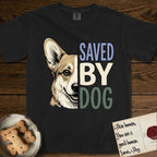 Saved by Dog Corgi T-Shirt flat lay in Black, featuring half a tan-and-cream Corgi's face in distressed vintage screen print, one upright ear and a foxy grin, cropped down the centerline beside bold stacked block lettering.