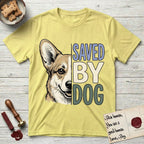 Saved by Dog Corgi T-Shirt flat lay in Cornsilk, featuring half a tan-and-cream Corgi's face in distressed vintage screen print, one upright ear and a foxy grin, cropped down the centerline beside bold stacked block lettering.