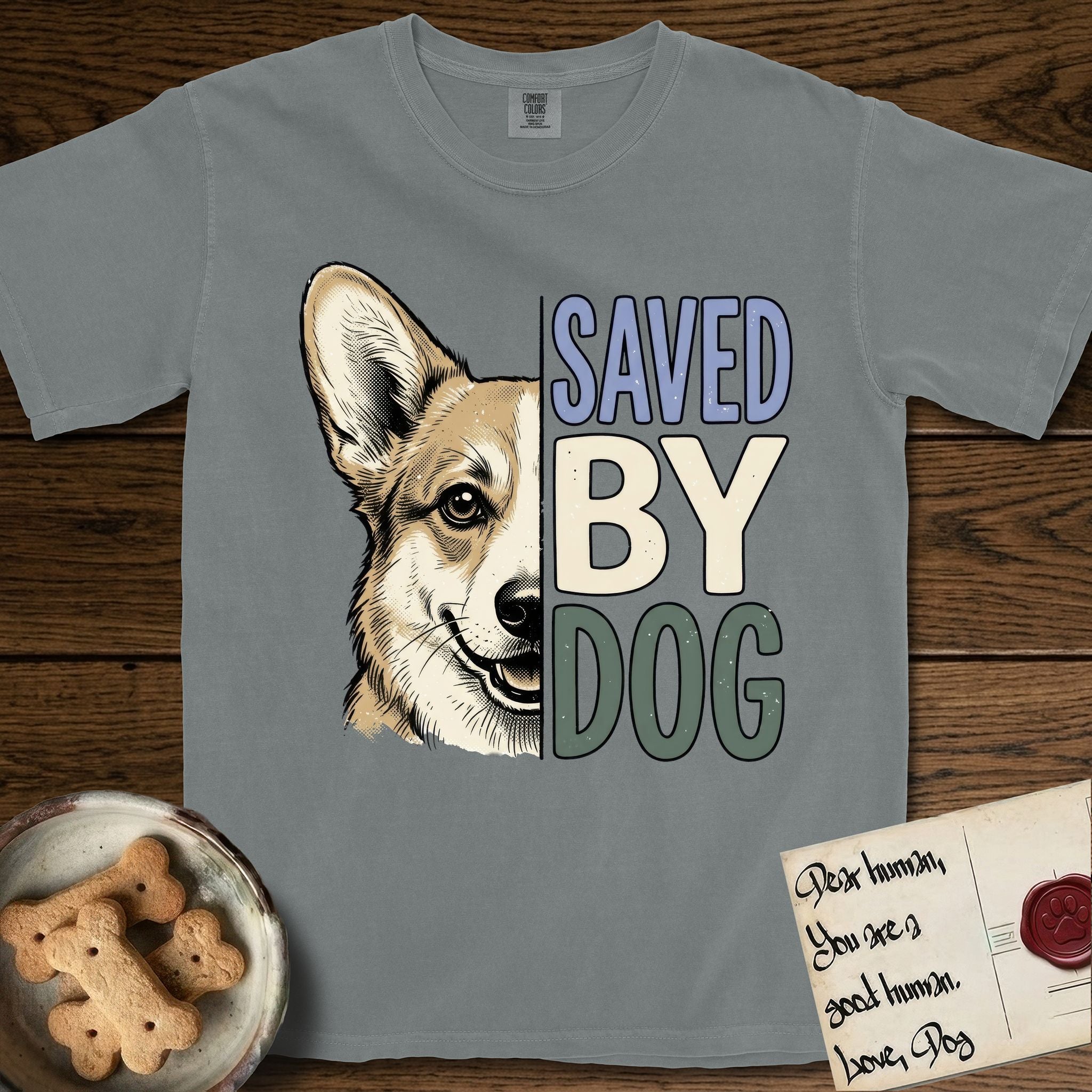Saved by Dog Corgi T-Shirt flat lay in Granite, featuring half a tan-and-cream Corgi's face in distressed vintage screen print, one upright ear and a foxy grin, cropped down the centerline beside bold stacked block lettering.