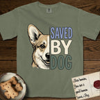 Saved by Dog Corgi T-Shirt flat lay in Sage, featuring half a tan-and-cream Corgi's face in distressed vintage screen print, one upright ear and a foxy grin, cropped down the centerline beside bold stacked block lettering.