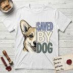 Saved by Dog Corgi T-Shirt flat lay in White, featuring half a tan-and-cream Corgi's face in distressed vintage screen print, one upright ear and a foxy grin, cropped down the centerline beside bold stacked block lettering.