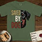 Saved by Dog Doberman T-Shirt flat lay in Moss, featuring half a black-and-rust Doberman's face in distressed vintage screen print, natural uncropped ears and a steady eye, cropped down the centerline beside bold stacked block lettering.