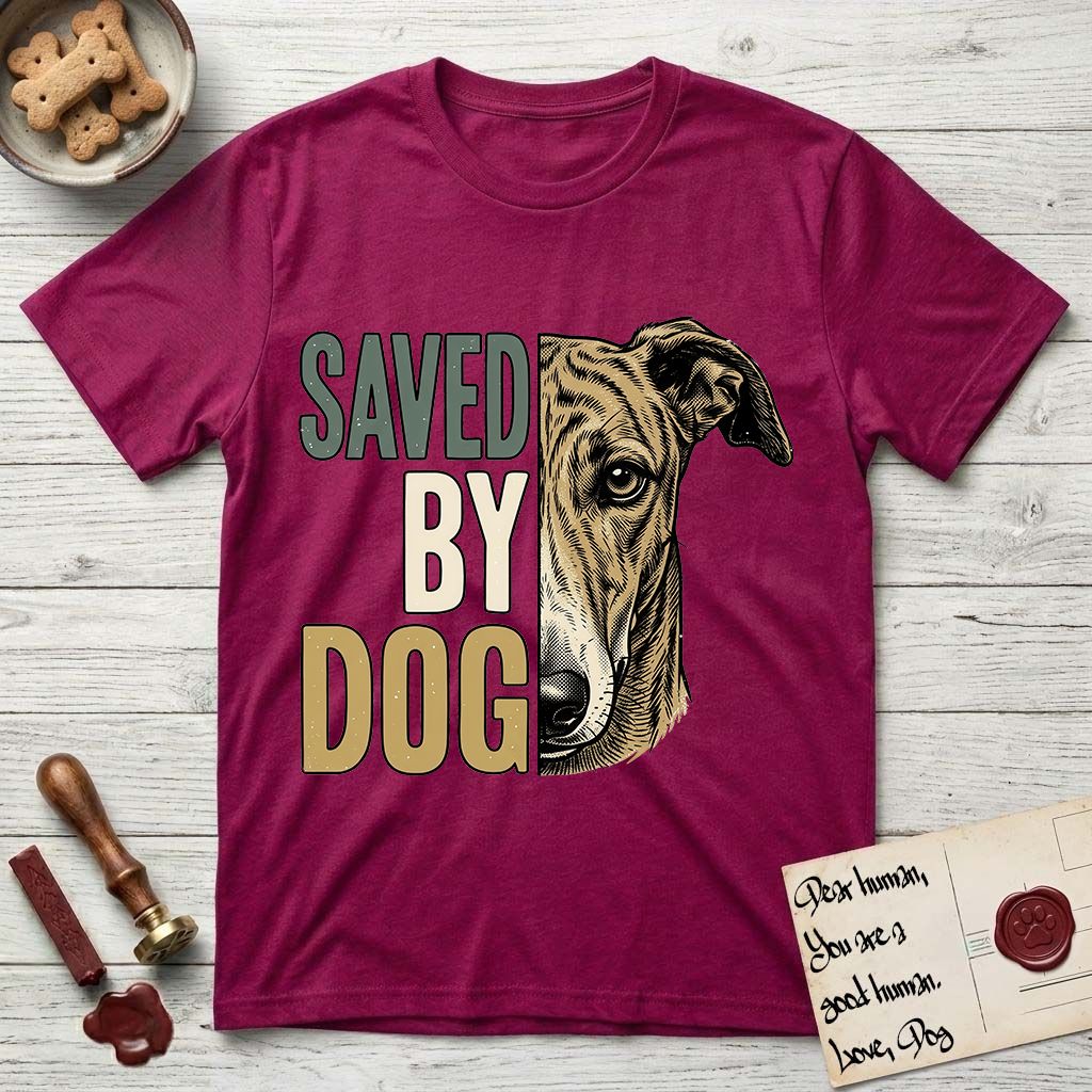 Saved by Dog Galgo T-Shirt flat lay in Antique Heliconia, featuring half a brindle Galgo's face in distressed vintage screen print, a folded rose ear and a gentle eye, cropped down the centerline beside bold stacked block lettering.