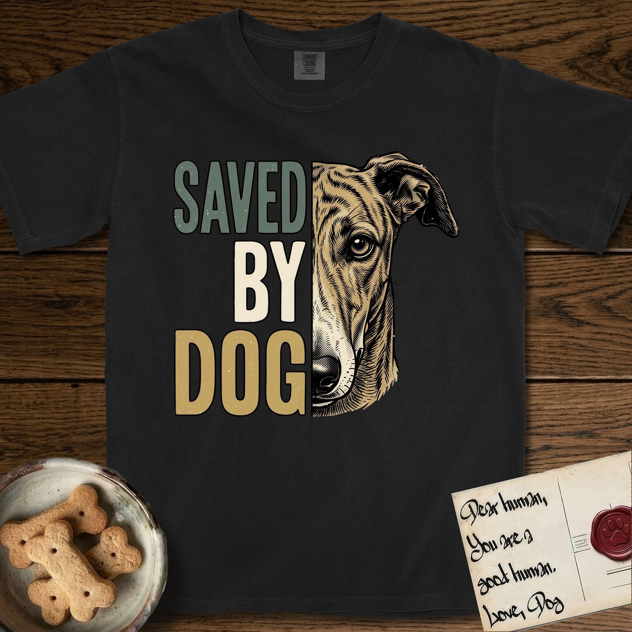 Saved by Dog Galgo T-Shirt flat lay in Black, featuring half a brindle Galgo's face in distressed vintage screen print, a folded rose ear and a gentle eye, cropped down the centerline beside bold stacked block lettering.