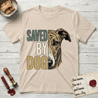 Saved by Dog Galgo T-Shirt flat lay in Sand, featuring half a brindle Galgo's face in distressed vintage screen print, a folded rose ear and a gentle eye, cropped down the centerline beside bold stacked block lettering.