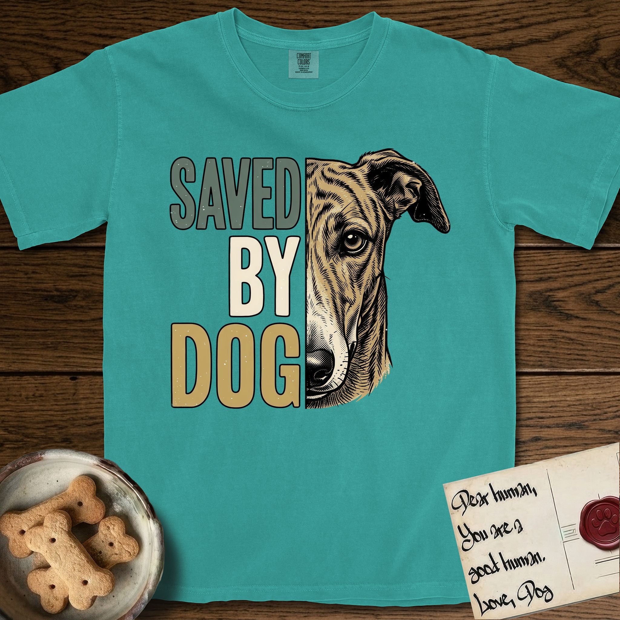 Saved by Dog Galgo T-Shirt flat lay in Seafoam, featuring half a brindle Galgo's face in distressed vintage screen print, a folded rose ear and a gentle eye, cropped down the centerline beside bold stacked block lettering.