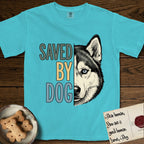 Saved by Dog Husky T-Shirt flat lay in Lagoon Blue, featuring half a black-and-white Husky's face in distressed vintage screen print, one pale ice-blue eye, cropped down the centerline beside bold stacked block lettering.