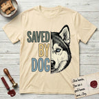 Saved by Dog Husky T-Shirt flat lay in Natural, featuring half a black-and-white Husky's face in distressed vintage screen print, one pale ice-blue eye, cropped down the centerline beside bold stacked block lettering.