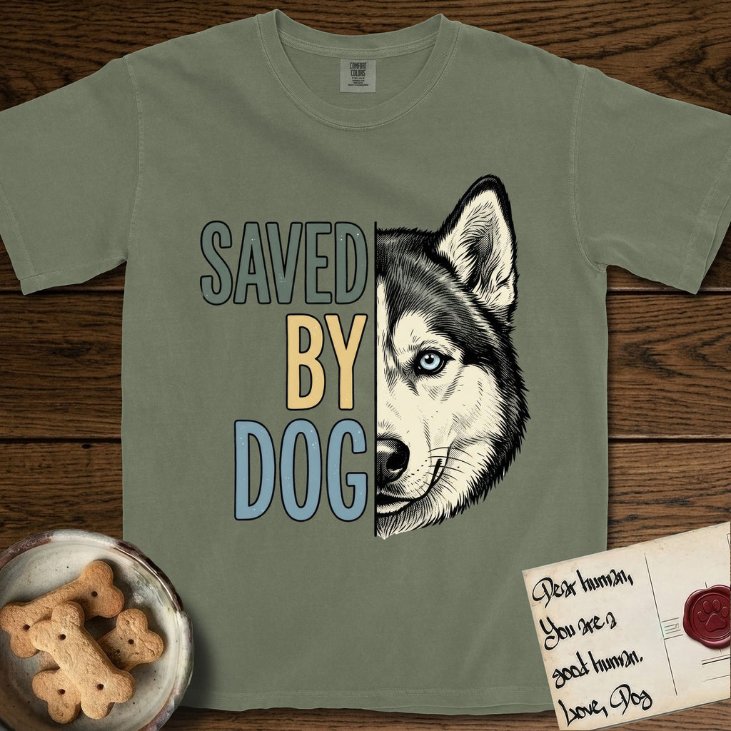 Saved by Dog Husky T-Shirt flat lay in Sage, featuring half a black-and-white Husky's face in distressed vintage screen print, one pale ice-blue eye, cropped down the centerline beside bold stacked block lettering.