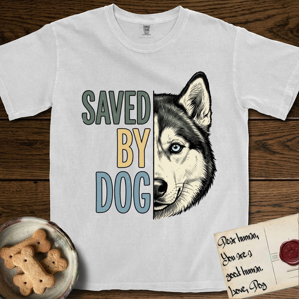 Saved by Dog Husky T-Shirt flat lay in White, featuring half a black-and-white Husky's face in distressed vintage screen print, one pale ice-blue eye, cropped down the centerline beside bold stacked block lettering.