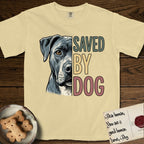 Saved by Dog Pitbull T-Shirt flat lay in Butter, featuring half a blue-grey Pitbull's face in distressed vintage screen print, one warm amber eye, cropped down the centerline beside bold stacked block lettering.