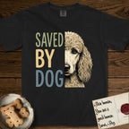 Saved by Dog Poodle T-Shirt flat lay in Black, featuring half an apricot Poodle's face in distressed vintage screen print, soft natural curls and a knowing eye, cropped down the centerline beside bold stacked block lettering.