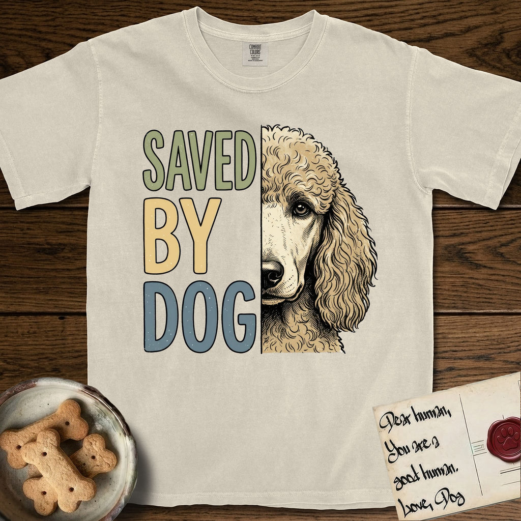 Saved by Dog Poodle T-Shirt flat lay in Ivory, featuring half an apricot Poodle's face in distressed vintage screen print, soft natural curls and a knowing eye, cropped down the centerline beside bold stacked block lettering.