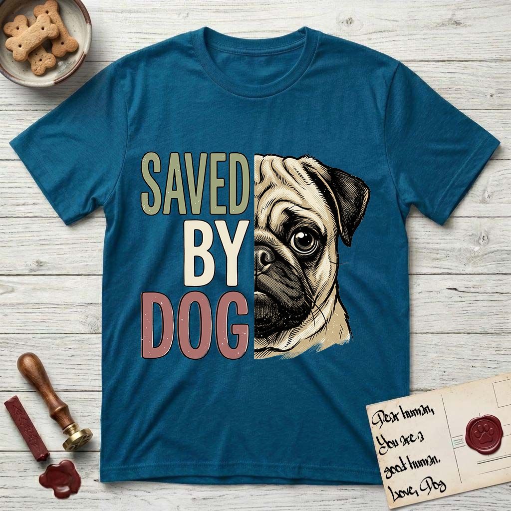 Saved by Dog Pug T-Shirt flat lay in Antique Sapphire, featuring half a fawn Pug's face in distressed vintage screen print, a dark mask and one large round eye, cropped down the centerline beside bold stacked block lettering.