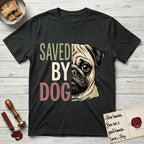 Saved by Dog Pug T-Shirt flat lay in Black, featuring half a fawn Pug's face in distressed vintage screen print, a dark mask and one large round eye, cropped down the centerline beside bold stacked block lettering.