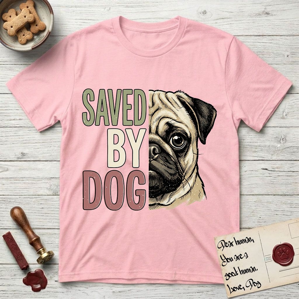 Saved by Dog Pug T-Shirt flat lay in Light Pink, featuring half a fawn Pug's face in distressed vintage screen print, a dark mask and one large round eye, cropped down the centerline beside bold stacked block lettering.