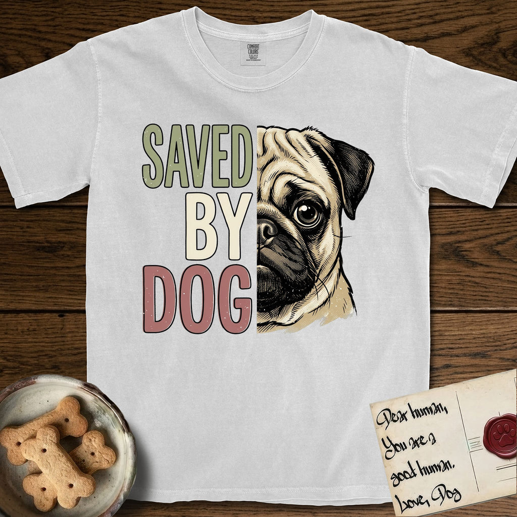 Saved by Dog Pug T-Shirt flat lay in White, featuring half a fawn Pug's face in distressed vintage screen print, a dark mask and one large round eye, cropped down the centerline beside bold stacked block lettering.
